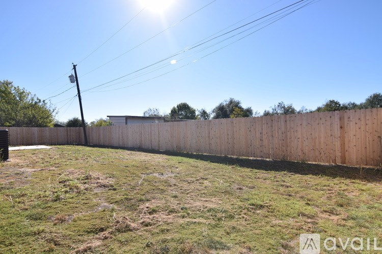 A wooden fence in a grassy area with a clear blue sky above.