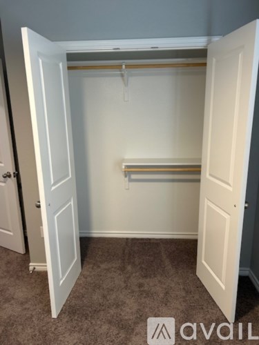 A white closet with a carpeted floor and a hanger bar.