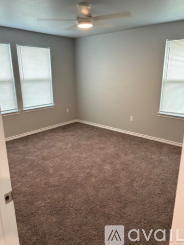 A room with a carpeted floor and a ceiling fan.