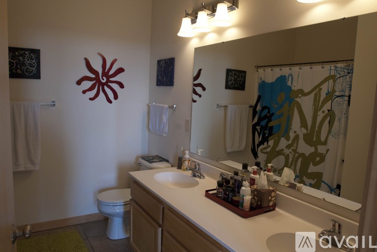 A bathroom with a toilet, sink, mirror, and a wall decoration.