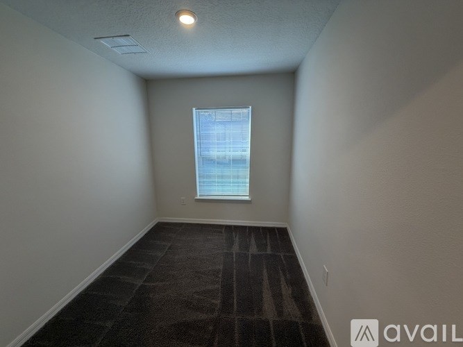 A room with a carpeted floor and a window with blinds.