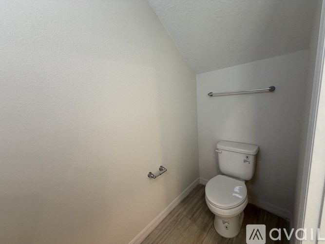 A white toilet in a small bathroom with a towel bar on the wall.