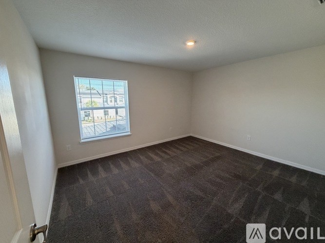 A room with a carpeted floor and a window showing a view of a parking lot.