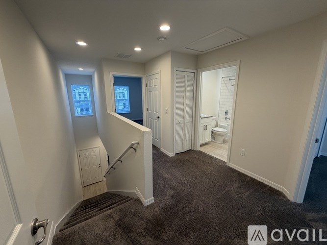 A room with a staircase leading to a second floor with a window and a door.