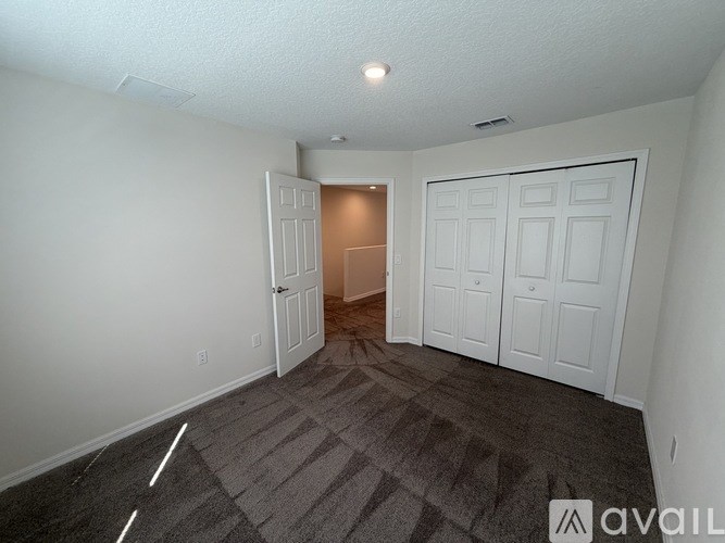 A room with a carpeted floor and two doors, one of which is open.