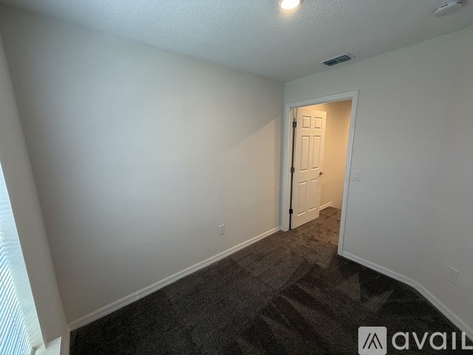 A room with a carpeted floor and a door leading to another room.