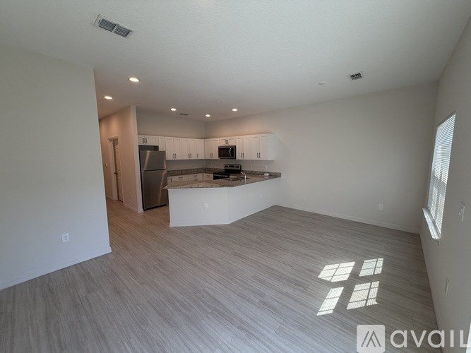 A spacious living room with a kitchen in the background.