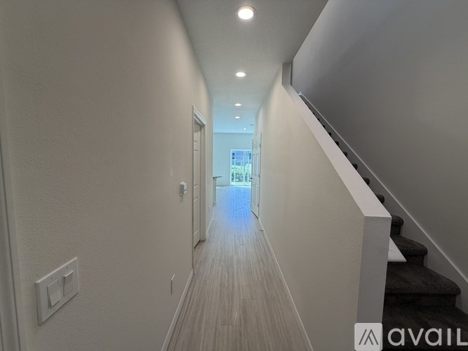 A long hallway with a staircase on the right and a door at the end.