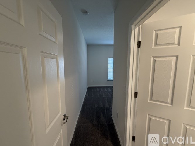 A hallway with white doors and a black floor.