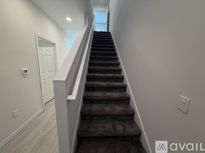 A staircase with a carpeted runner and white walls.