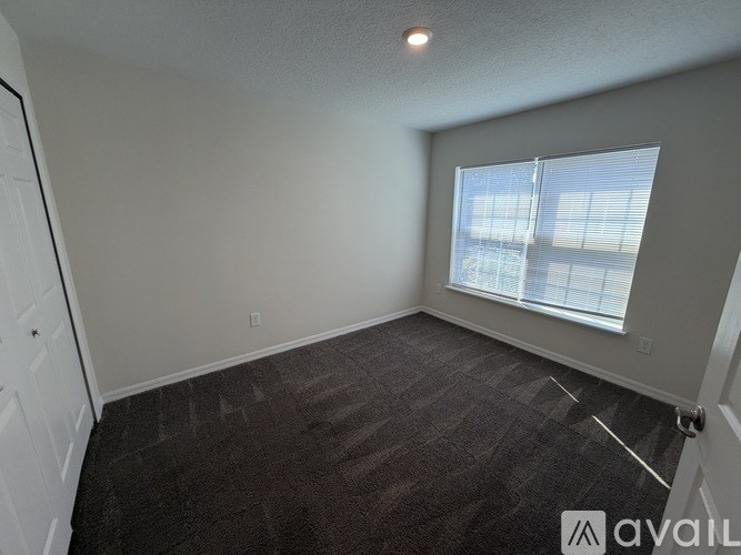 A room with a carpeted floor and a window with blinds.