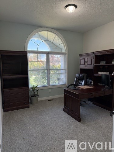 A room with a desk and a window with blinds.