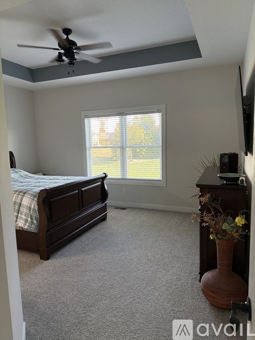 A bedroom with a bed, dresser, and window.