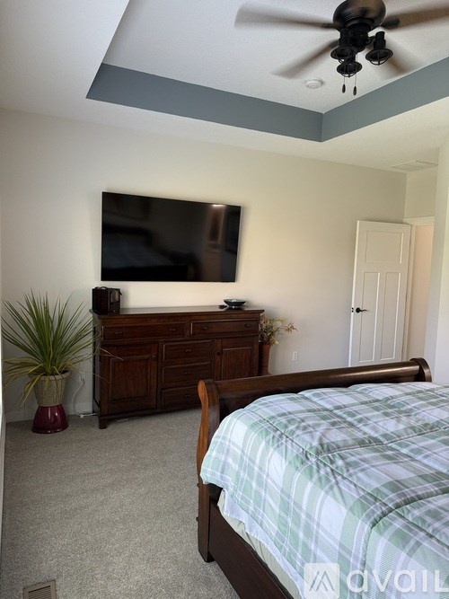 A bedroom with a bed, dresser, and ceiling fan.