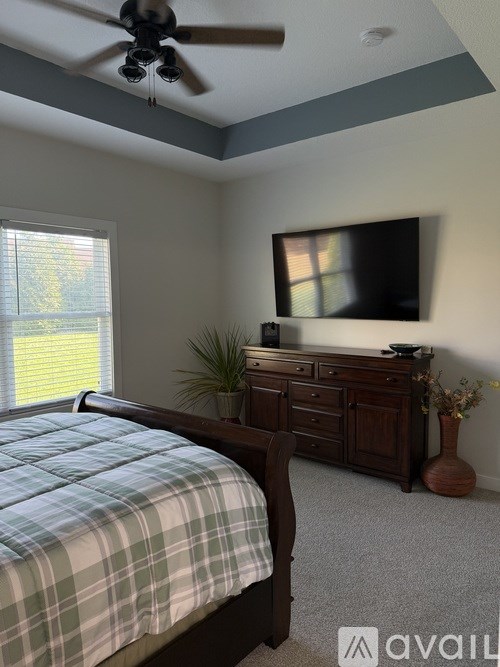 A bedroom with a bed, dresser, and television.