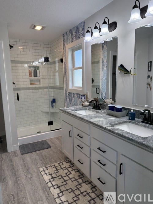 A bathroom with a walk-in shower, double sinks, and a large mirror.