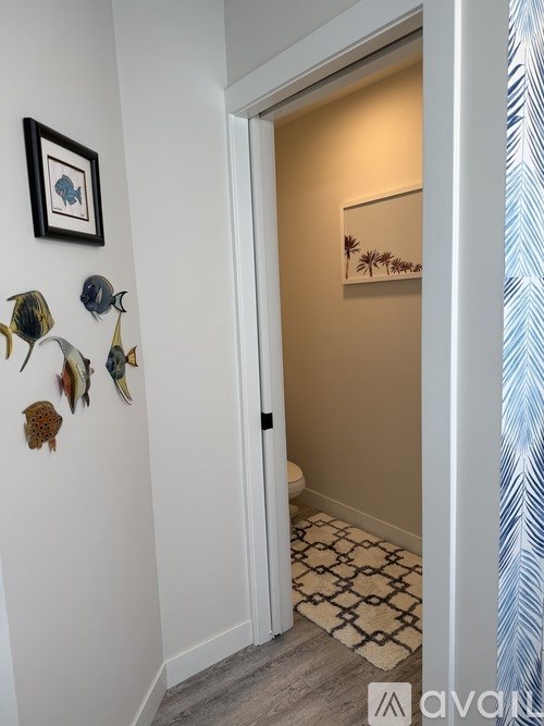 A hallway with a doorway leading to a bathroom with a framed picture on the wall.