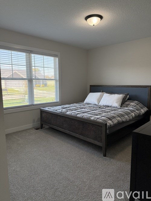 A bedroom with a bed, carpet, and a window.