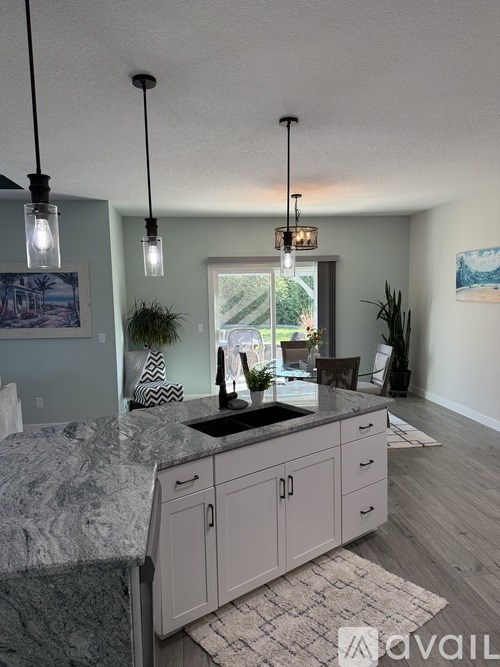 A kitchen with granite countertops and pendant lights.