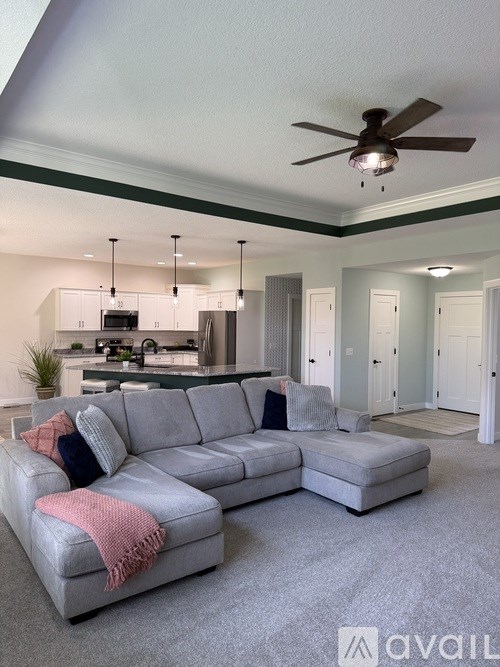 A living room with a grey sofa and a ceiling fan.