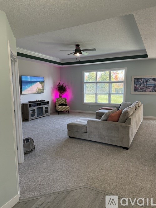 A living room with a grey couch and a ceiling fan.