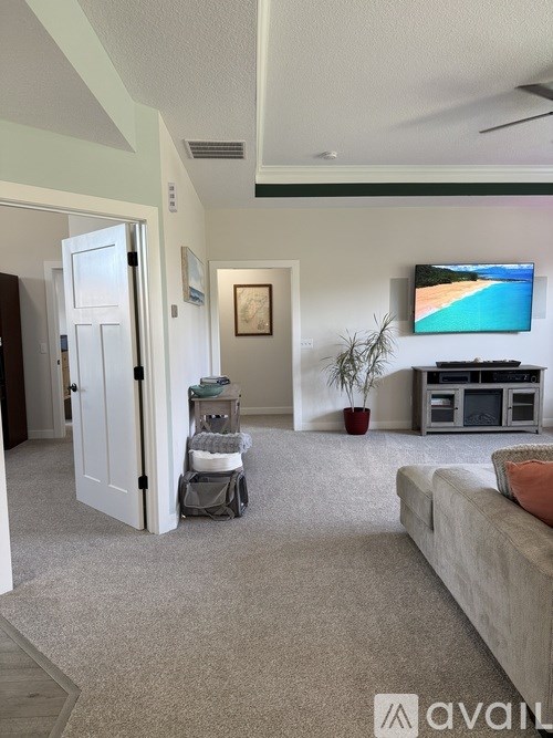 A living room with a grey sofa and a television on the wall.