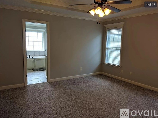 A room with a carpeted floor, a ceiling fan, and a window with blinds.