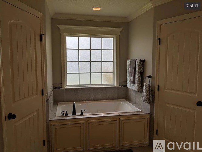 A bathroom with a window above a bathtub and two sinks.