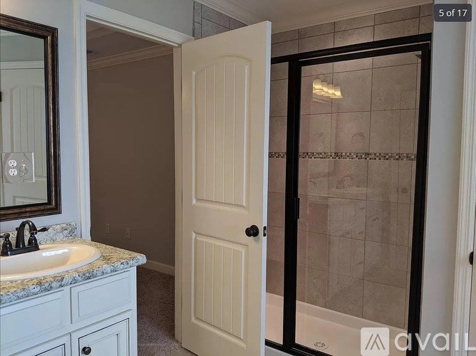 A bathroom with a sink, mirror, and a shower with a glass door.