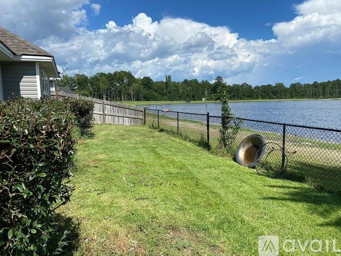 A fenced area with a grassy field and a lake in the distance.