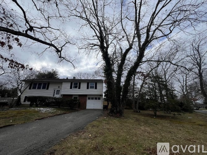 A house with a driveway and trees in front of it.