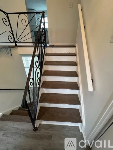 A staircase with a black wrought iron railing and wooden steps.