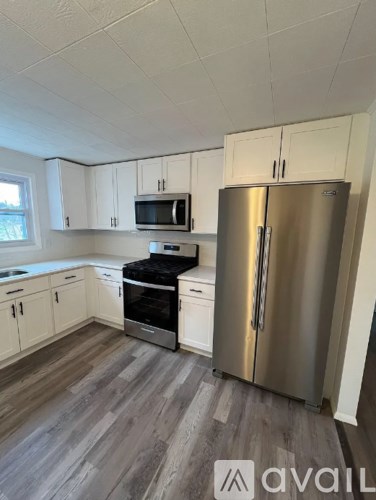 A kitchen with a stainless steel refrigerator and wooden floors.