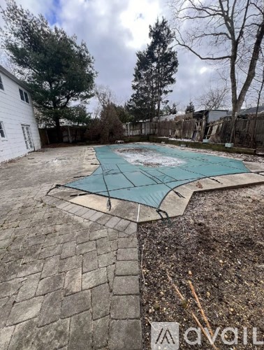 A backyard with a pool covered in a green tarp.