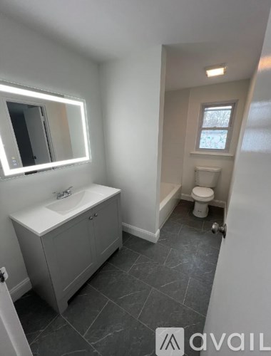 A bathroom with a sink, toilet, and a window.