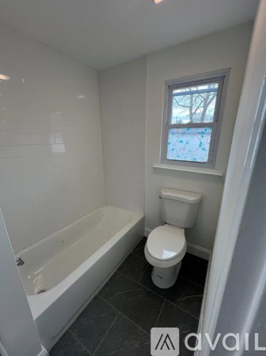 A small bathroom with a toilet, tub, and window.