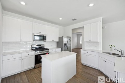 A modern kitchen with white cabinets and appliances.