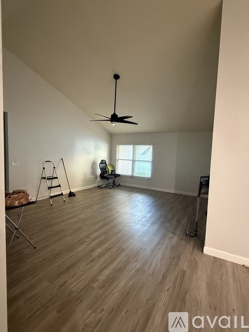 A room with a ceiling fan and a person sitting on a chair.