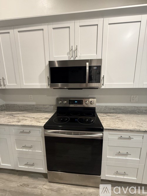 A kitchen with white cabinets and a black stove top oven.