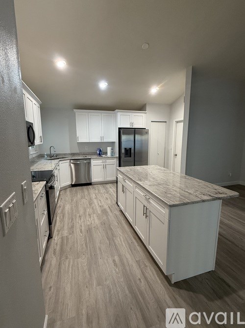 A kitchen with a refrigerator, sink, and cabinets.