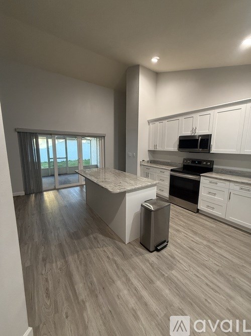 A modern kitchen with white cabinets and a wooden floor.