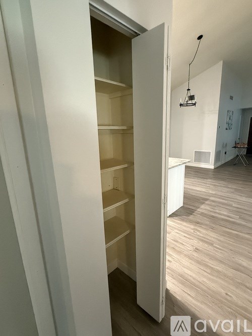 A white open doorway leads to a room with a wooden floor.