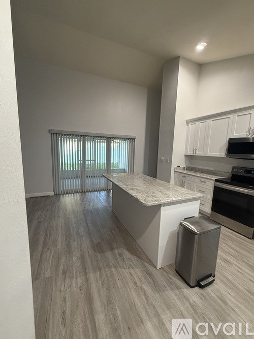 A kitchen with a trash bin in the middle of the room.