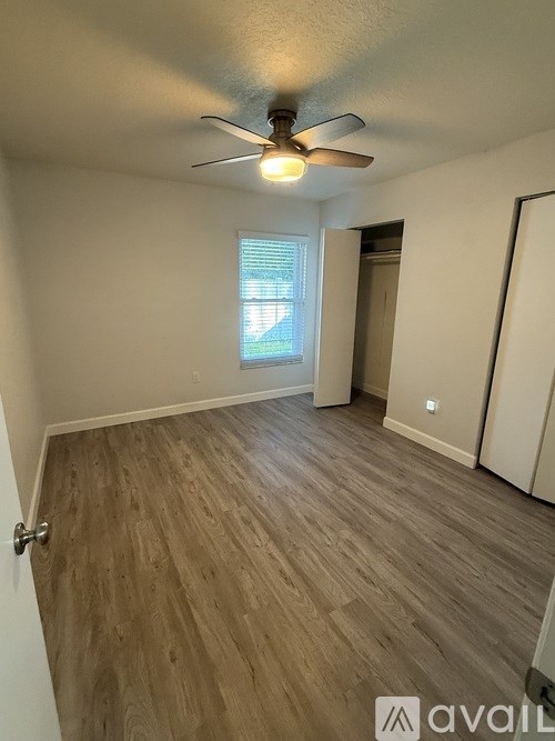 A room with a ceiling fan and wooden flooring.