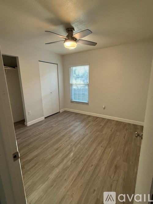 A room with a ceiling fan and wooden flooring.
