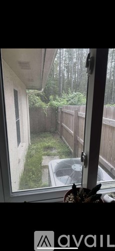 A view from a window looking out to a backyard with a wooden fence and trees.