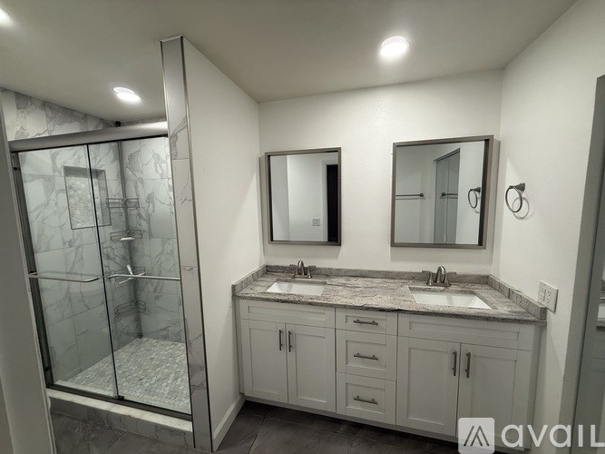 A bathroom with a walk-in shower and double sinks.
