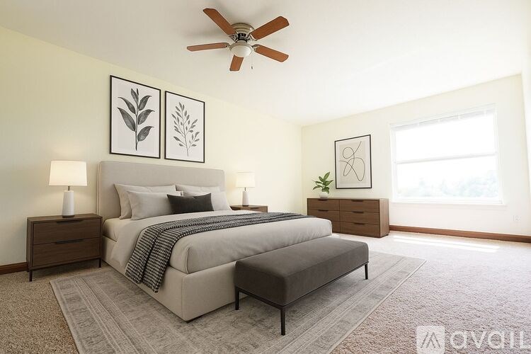 A bedroom with a large bed, a ceiling fan, and two framed pictures on the wall.