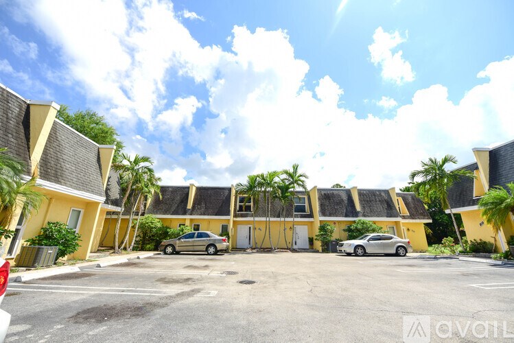 A sunny day at the parking lot with cars and palm trees.