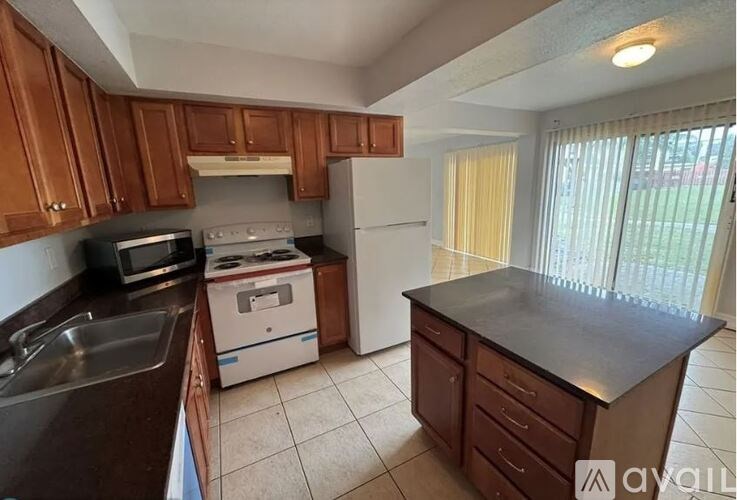 A kitchen with brown cabinets and a black countertop.